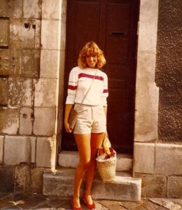 Chris at age 22 in front of her French apartment shopping with a basket and baguette