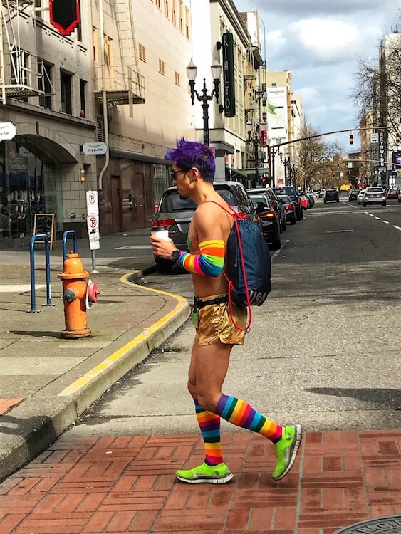 A rainbow clad Portlander crosses the street