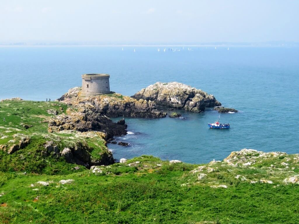 rocky peninsula in truquoise water and grassy meadow