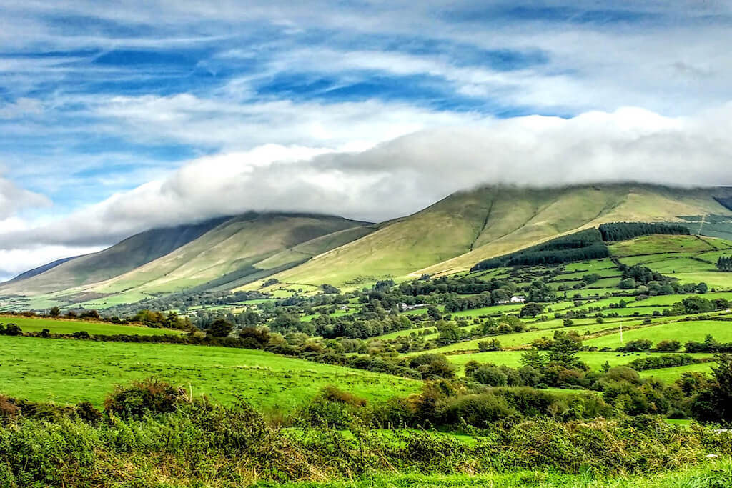 Green meadow with green hills and a sultry summer sky with wispy clouds at Glen of Aherlow tipperary