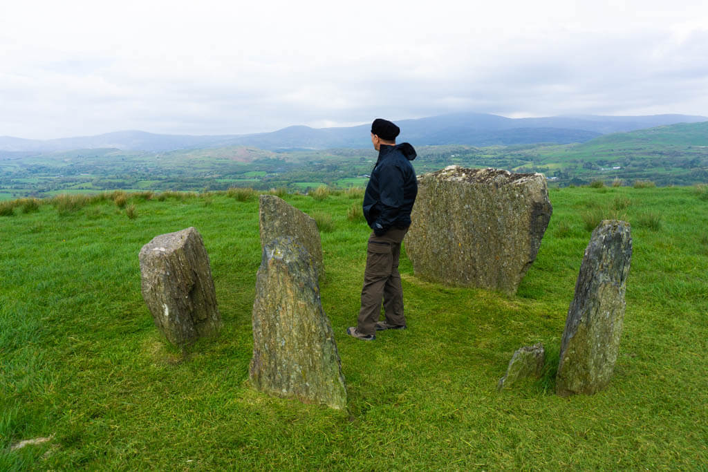 Man standing inside a prehistoric stone circle high on a hill
