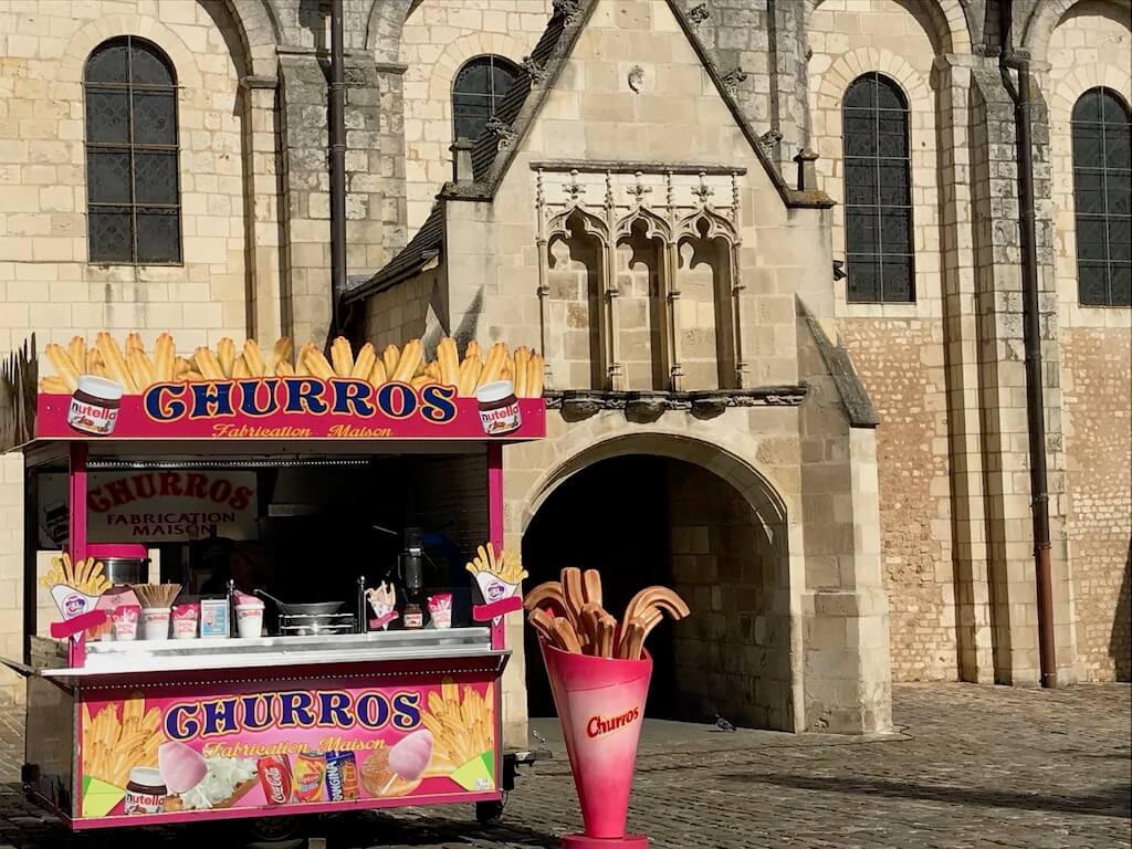 Facade of Notre Dame Cathedral with a hot pink churro stand in front