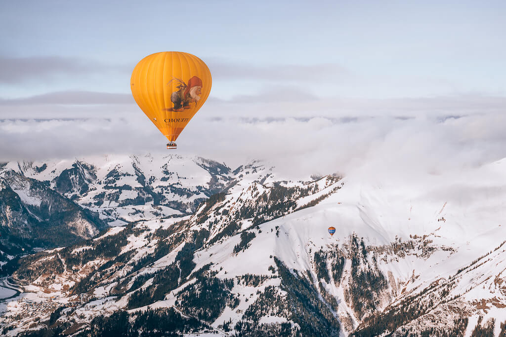 Brightly colored balloons floating above snowy mountain peaks in Chateau d'Oeux