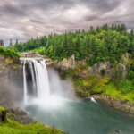 waterfall surrounded by forest and moody clouds