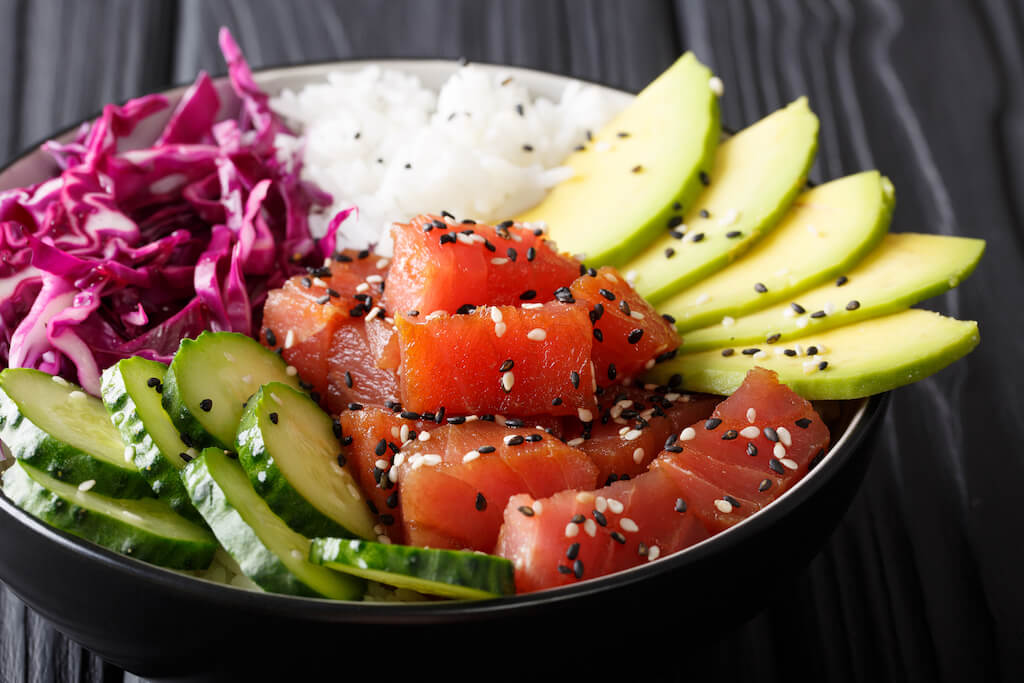 Raw Organic Ahi Tuna Poke Bowl with Rice and Veggies close-up on the table. 