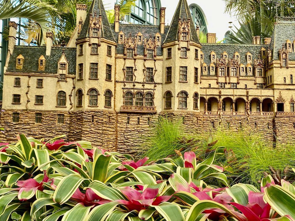 colorful bromeliad plants in front of replica of biltmore Mansion