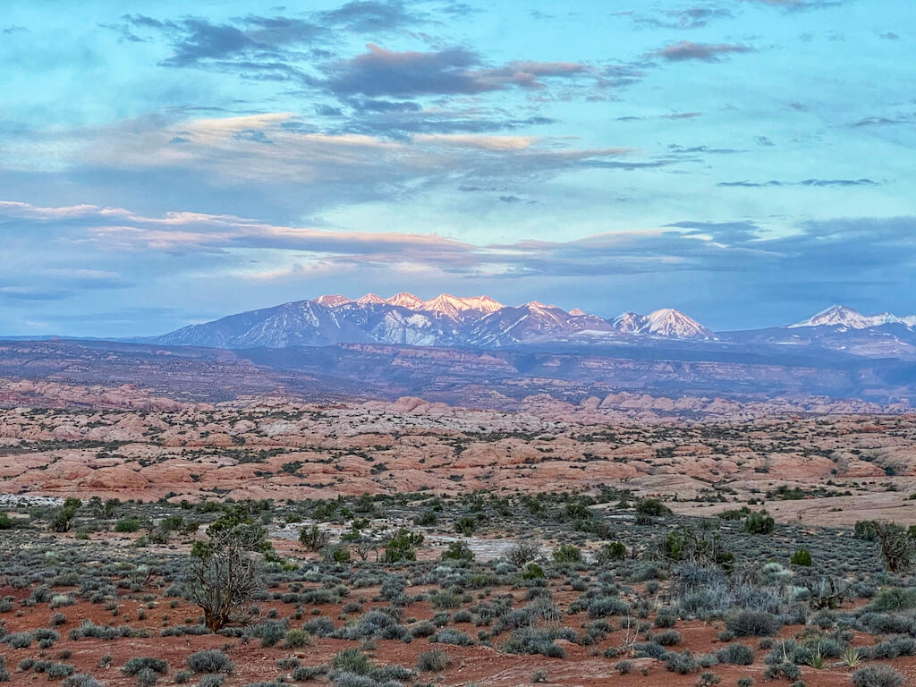 snowcapped mountains backlit at sunset with desert in foreground