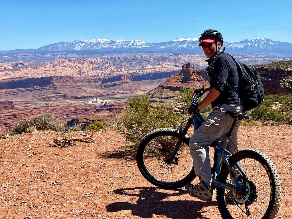 man on mountain bike with canyons and mountains in distance