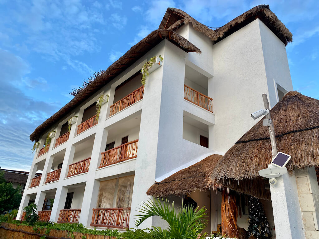 exterior of stucco hotel with palapa roof