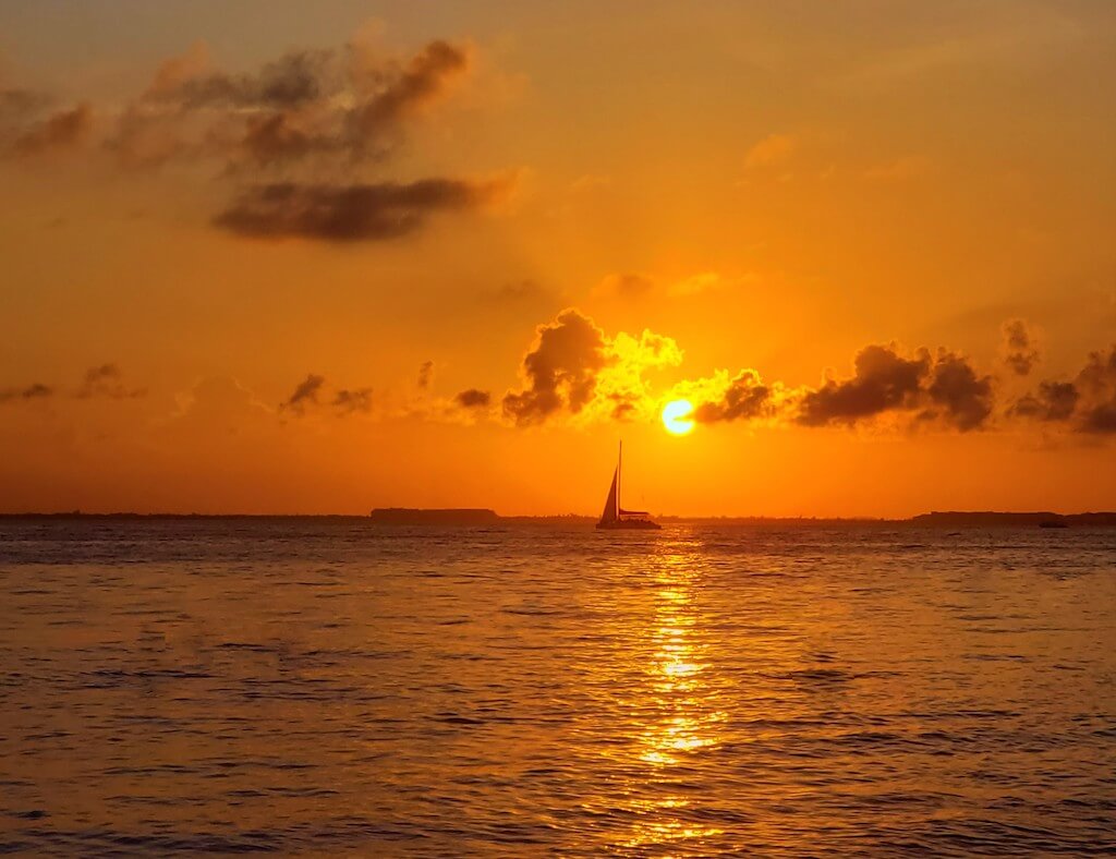 sun setting over a sailboat on Isla Mujeres