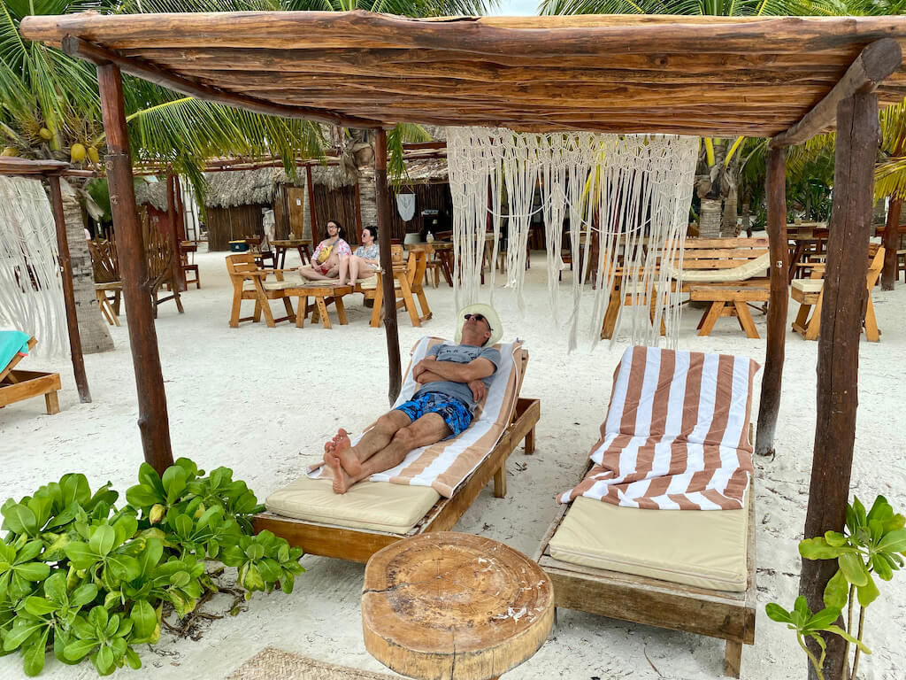 man sleeping on a lounger on a white sand beach