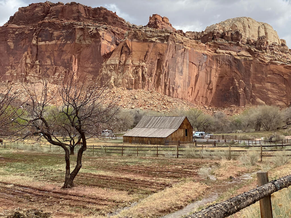 historic barn in front of steep red cliffs