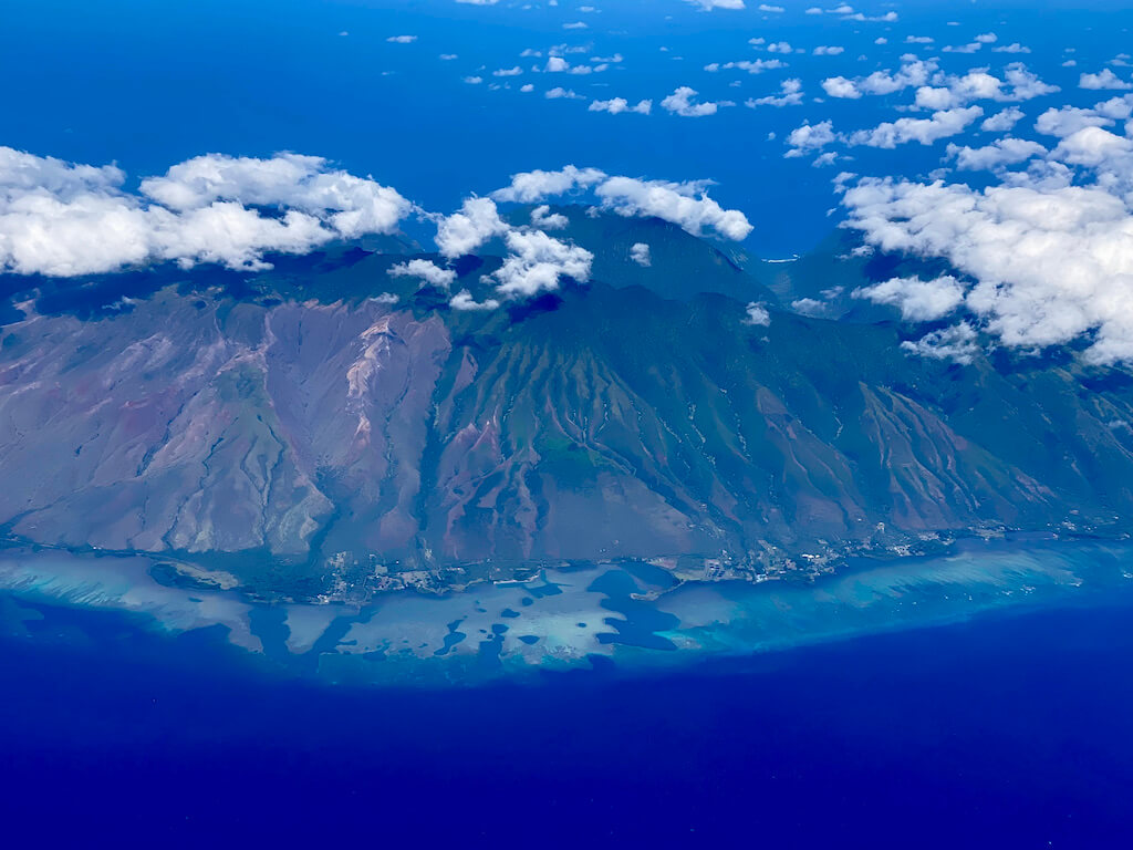 View of Oahu's green mountains and shallow reefs from the airplane