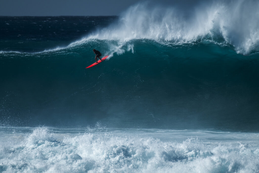 Extreme surfer rides gigantic ocean wave at Waimea Bay surf spot. The North Shore of Oahu, Hawaii