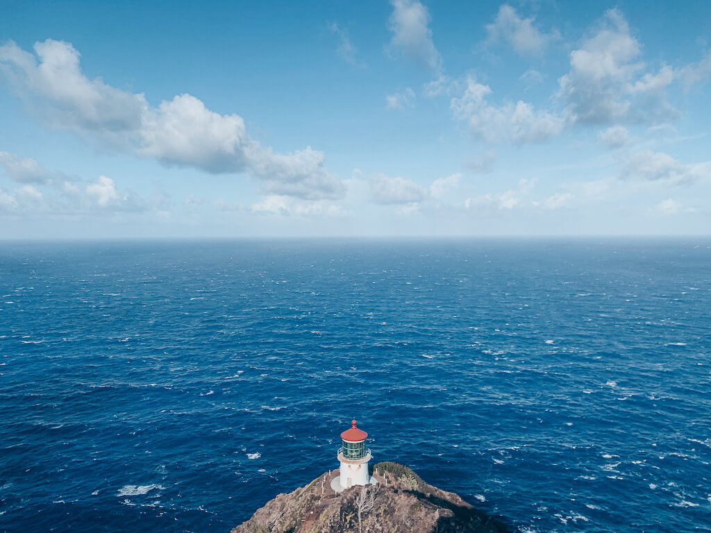 Lighthouse on a point with white capped ocean all around