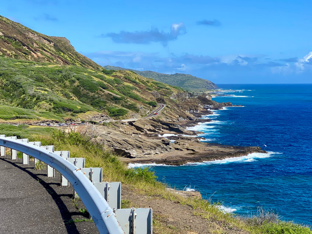 Scenic highway snaking around green cliffs and deep blue ocean with white caps