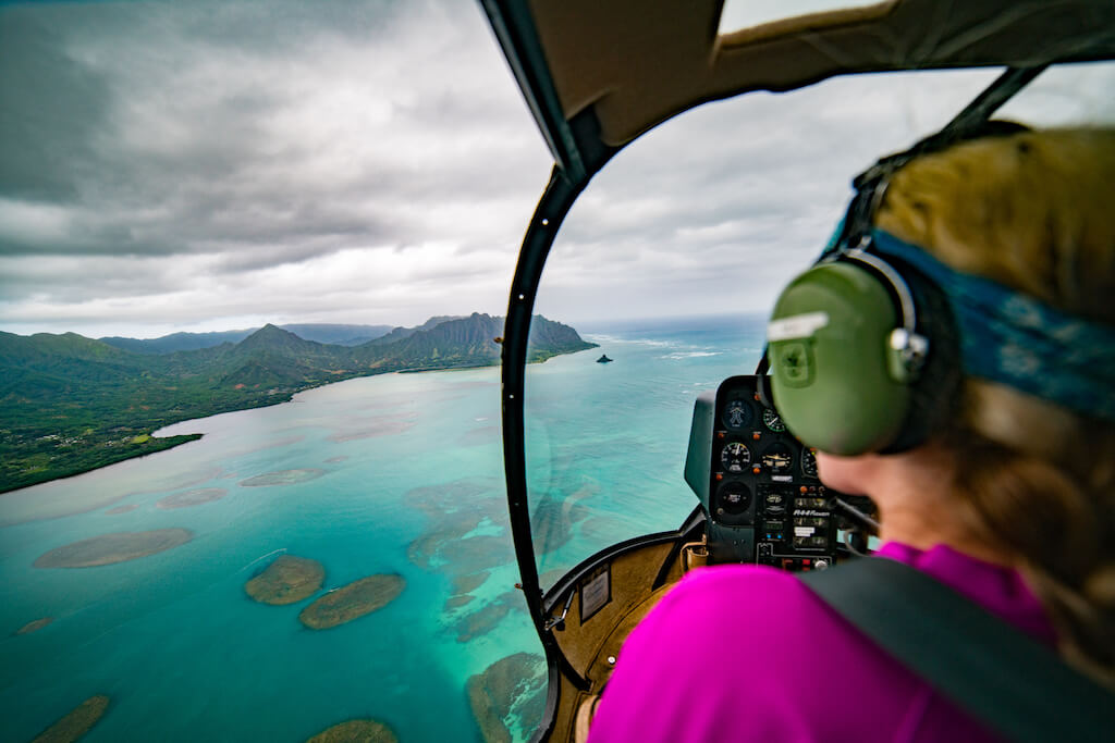 woman in an open door helicopter above the ocean