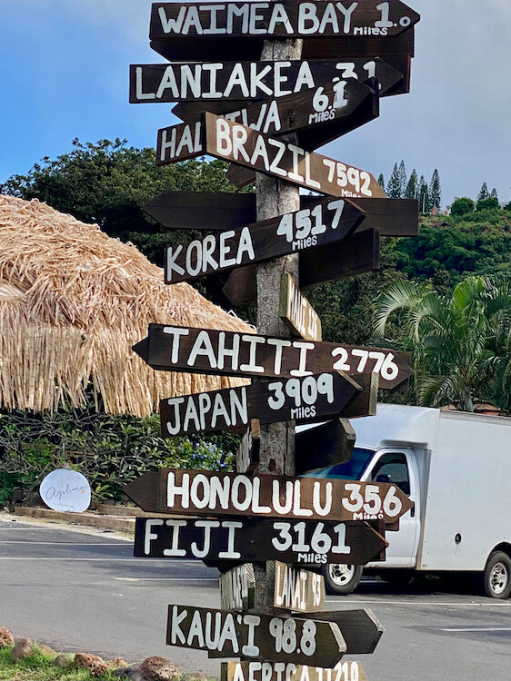 Vertical sign post with mileage to cities in various Hawaiian islands