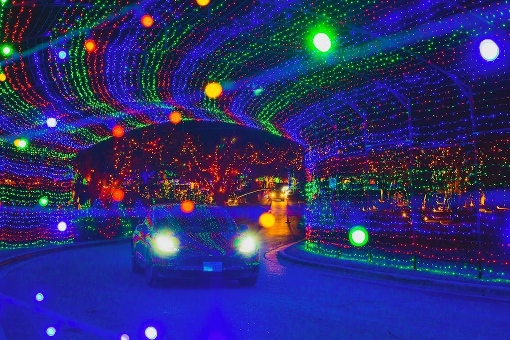 car driving through a tunnel of colored lights at night