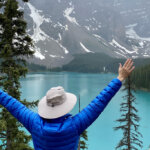 woman with arms up admiring Moraine Lake