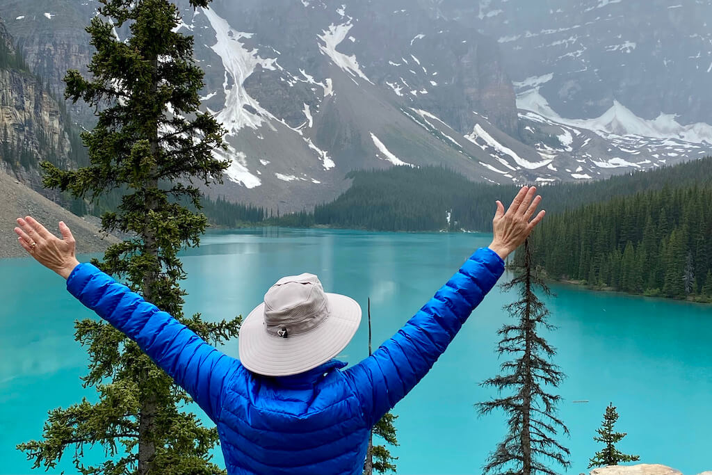 woman with arms up admiring Moraine Lake