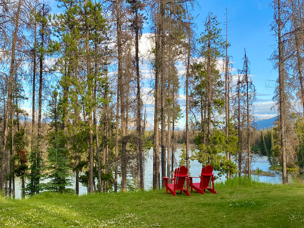 two red adirondack chairs by a river in Jasper