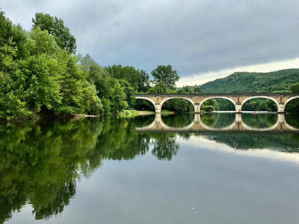 reflection of a scenic bridge on Dordgone River opposite Chateau de Beynac