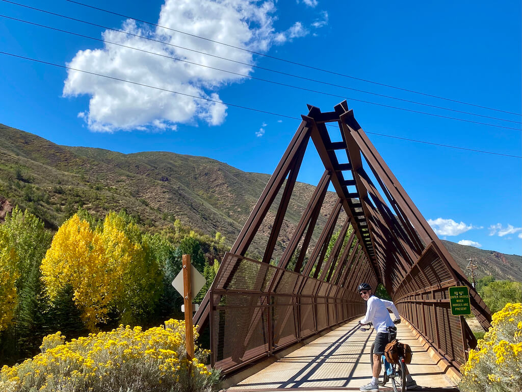 man on a bike in front of a triangular metal bridge