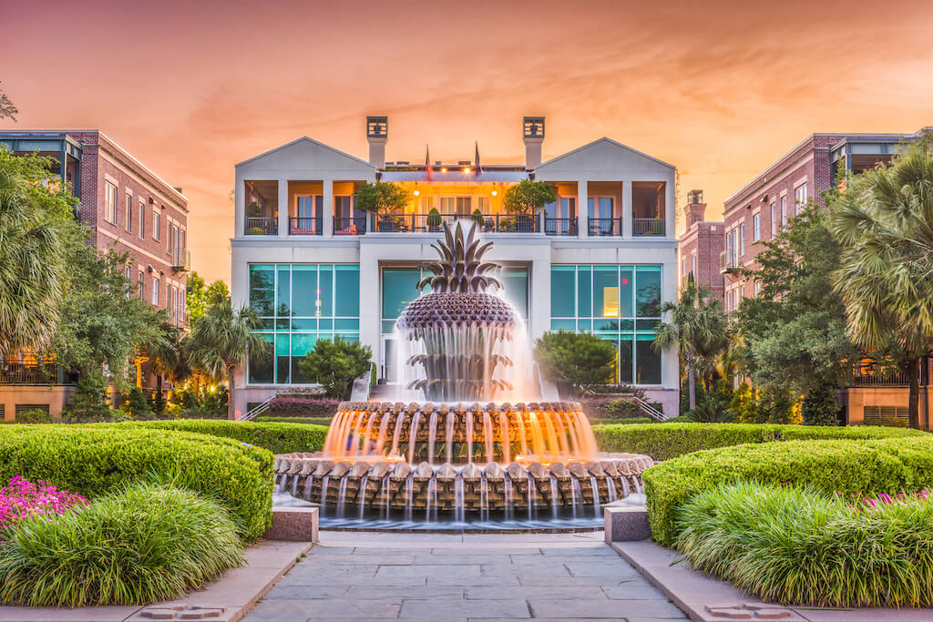 view of pineapple fountain with mansion and sunset in background