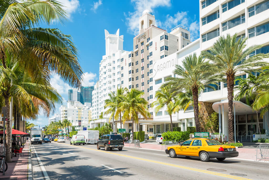 Famous art deco hotels and traffic at Collins Avenue on a sunny day at Miami Beach