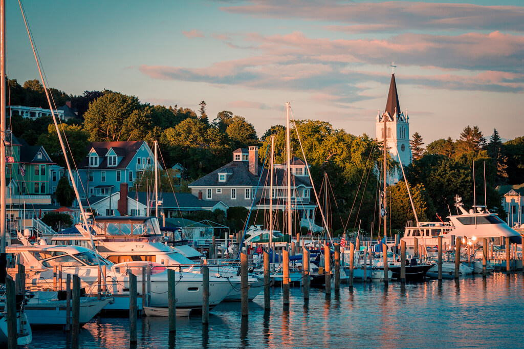 The Marina at Mackinac Island with Saint Anne's church and the historic victorian houses at sunset