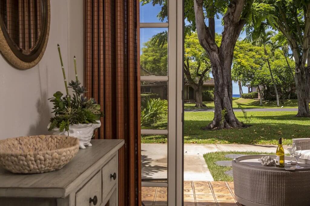 view of lush tropical grounds and ocean from doorway of condo