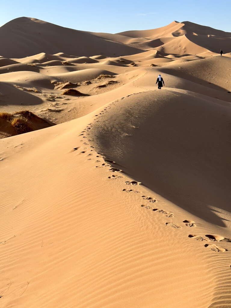 man walking through the san dunes in Merzouga, Sahara Desert