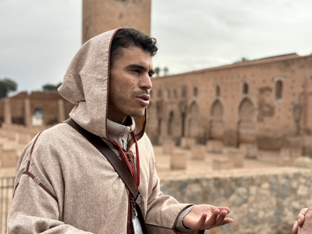 Moroccan tour guide explaining in front of Koutubia Mosque in Marrakech.