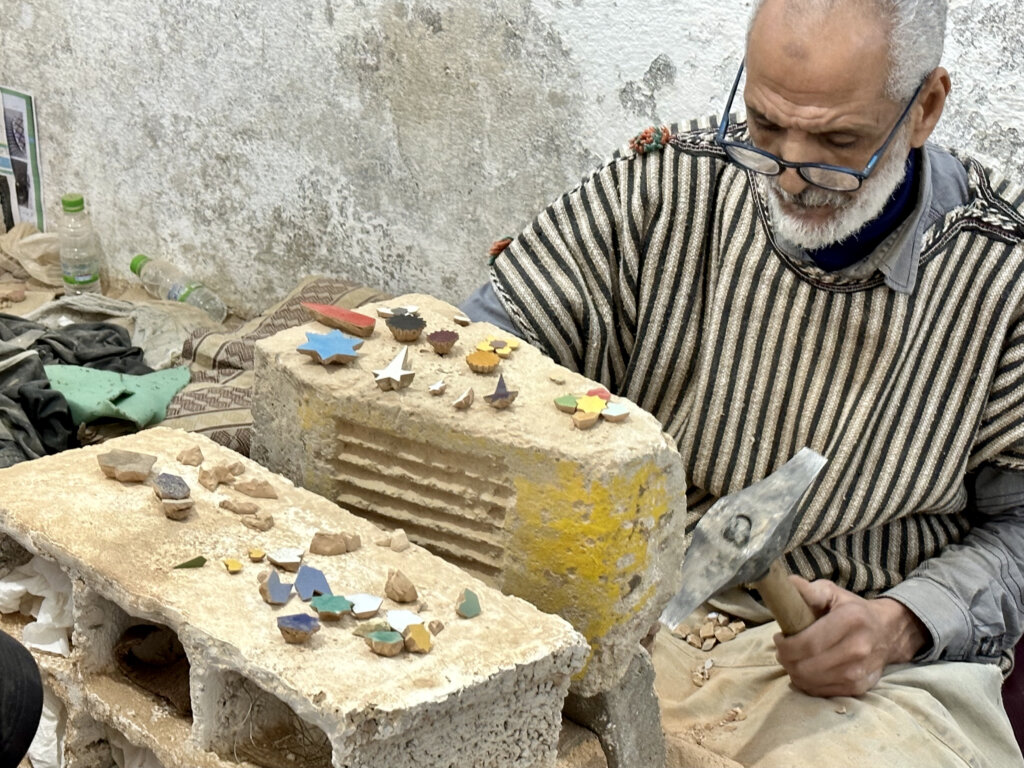artisan hammering Zellij tile in Fes factory.