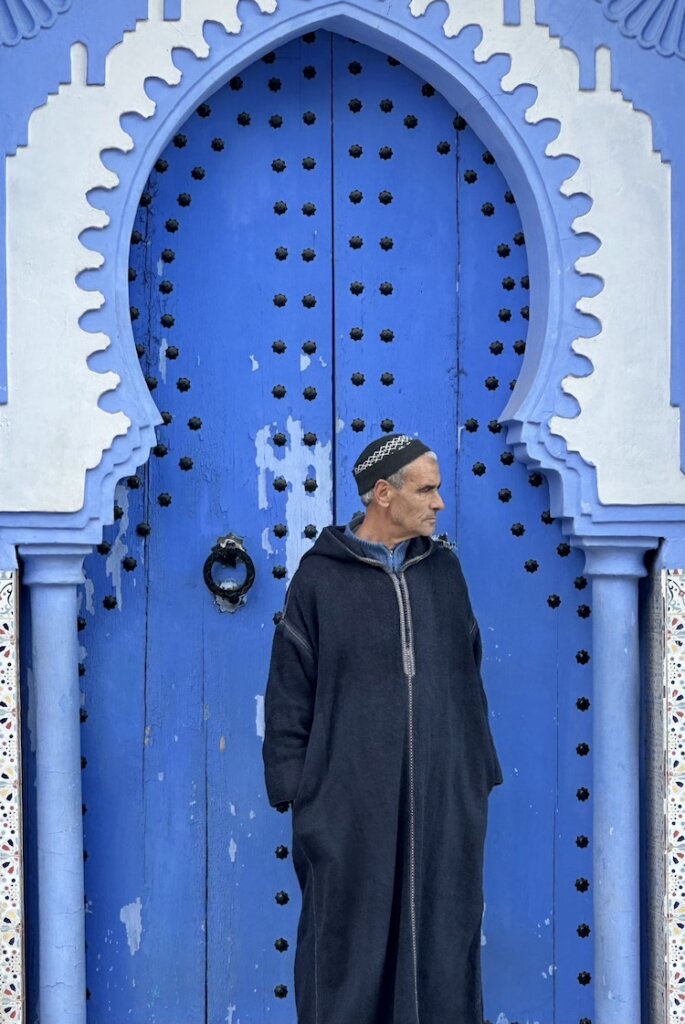Man in front of a blue door in Chefchouan