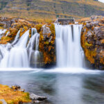 Kirkjufellsfoss waterfall in southern Iceland with bright yellow fall lichen