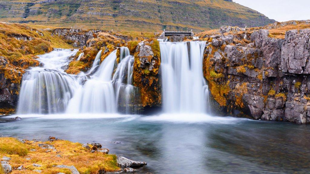 Kirkjufellsfoss waterfall in southern Iceland with bright yellow fall lichen