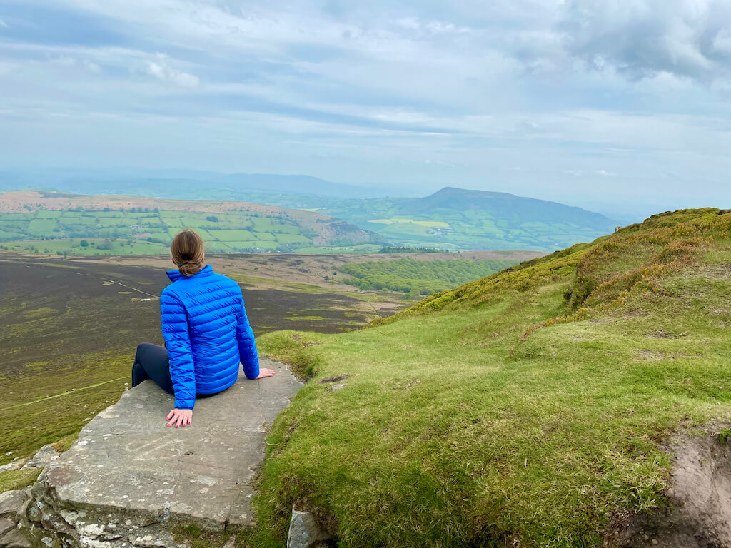 woman sitting on a rock looking at a scenic vista in Wales